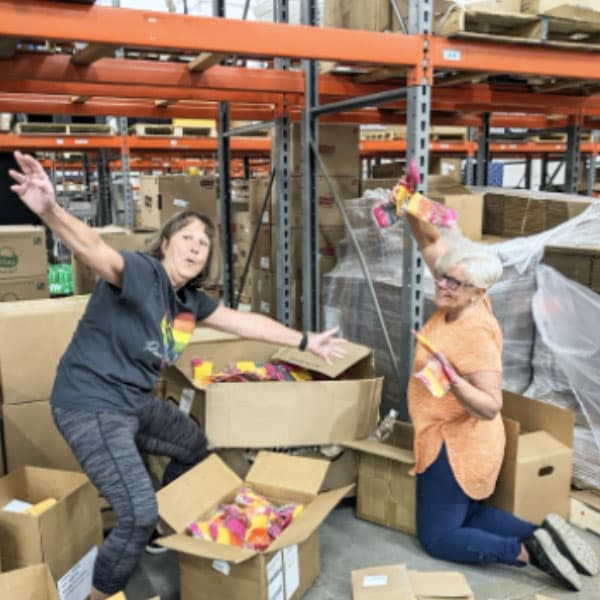 Volunteers with different donor appreciation items in a warehouse.