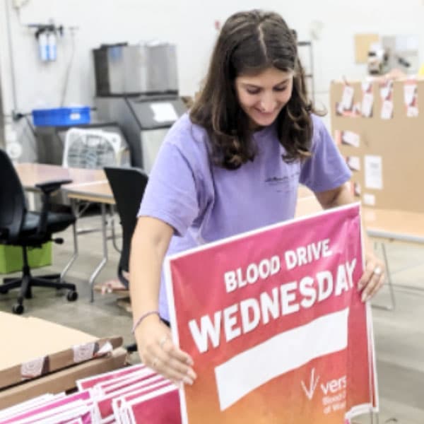 Volunteer with a "Blood Drive Wednesday" sign.